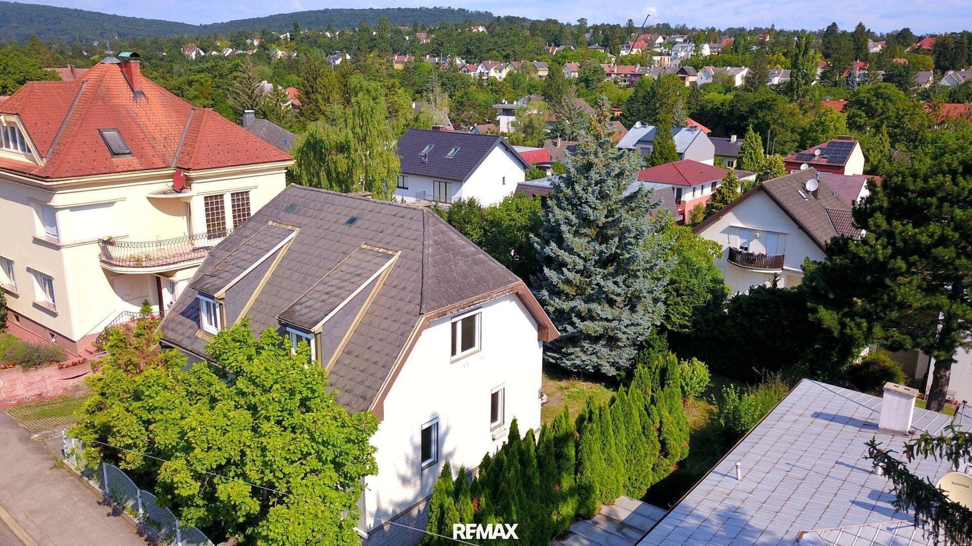 Weitläufige Luftaufnahme des Hauses inmitten einer grünen Wohngegend.