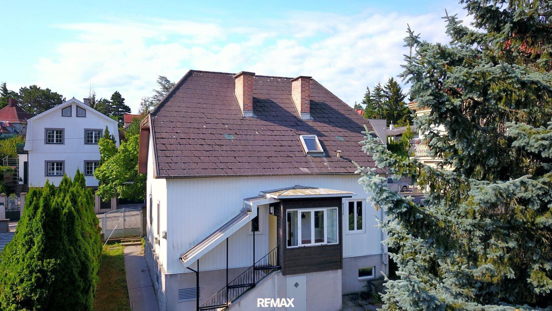Luftaufnahme des Einfamilienhauses mit Mansarddach und umliegenden Bäumen.