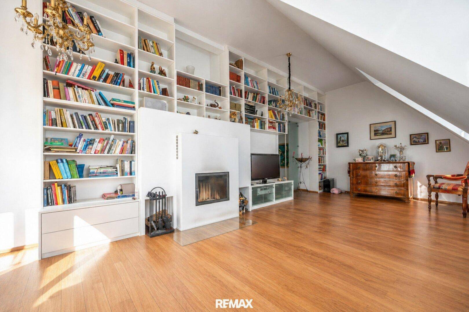 Elegantes Wohnzimmer mit Holzboden, raumhohen Bücherregalen und modernem Kamin als Blickfang.