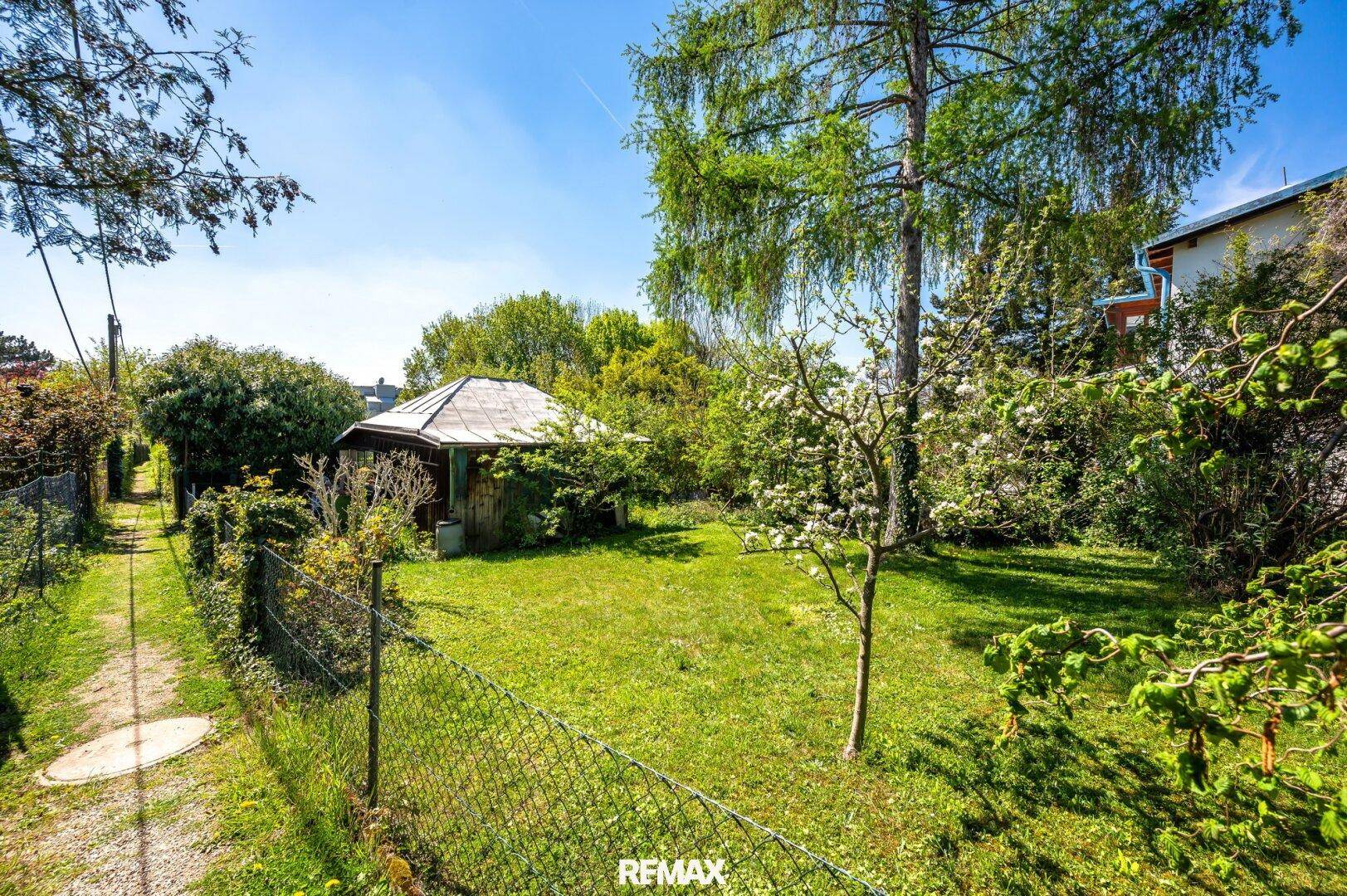 Gartenweg führt durch die grüne Anlage, vorbei an einem Zaun und dem charmanten Holzpavillon.