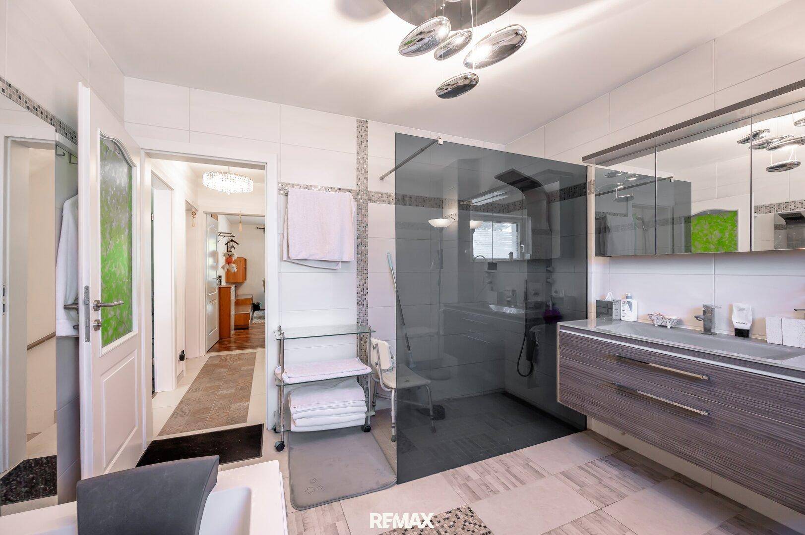 Geräumiges Badezimmer mit Doppelwaschbecken, großer Glasdusche und modernem Design.