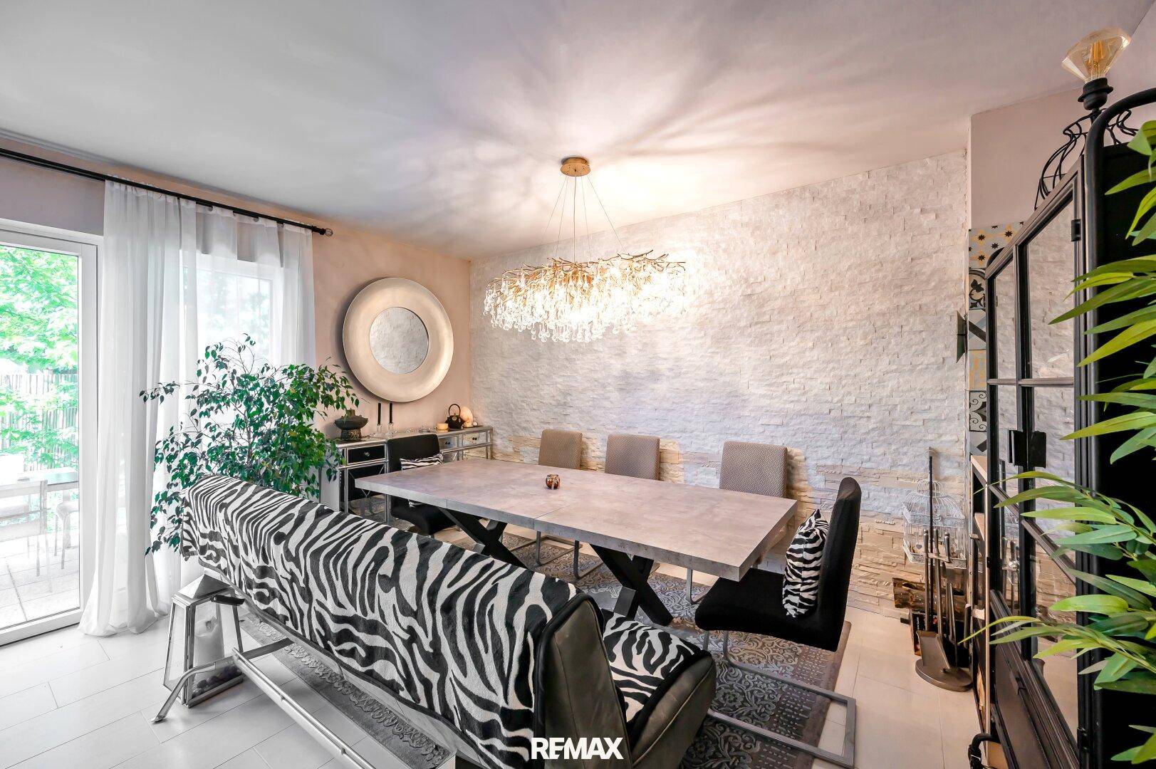 Heller Essbereich mit modernem Esstisch, dekorativer Steinwand und Zugang zur Terrasse.