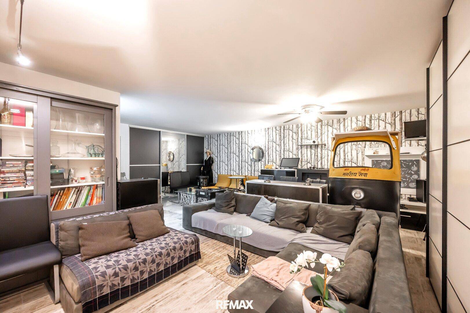 Geräumiger Wohnbereich mit großem Sofa, Bücherregal und auffälliger Tapete.