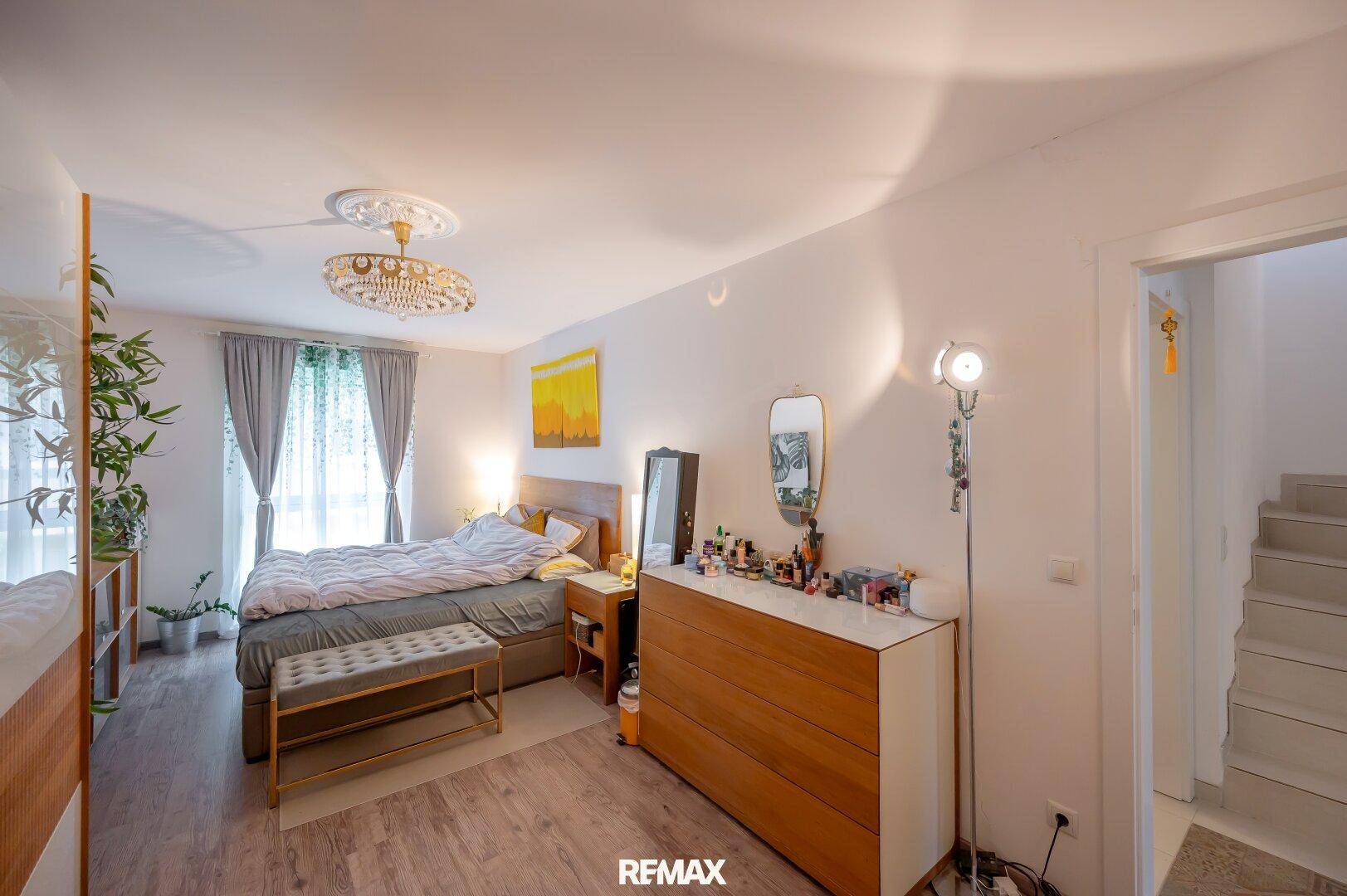 Gemütliches Schlafzimmer mit Doppelbett, Holzkommode und Zugang zu einem weiteren Bereich.