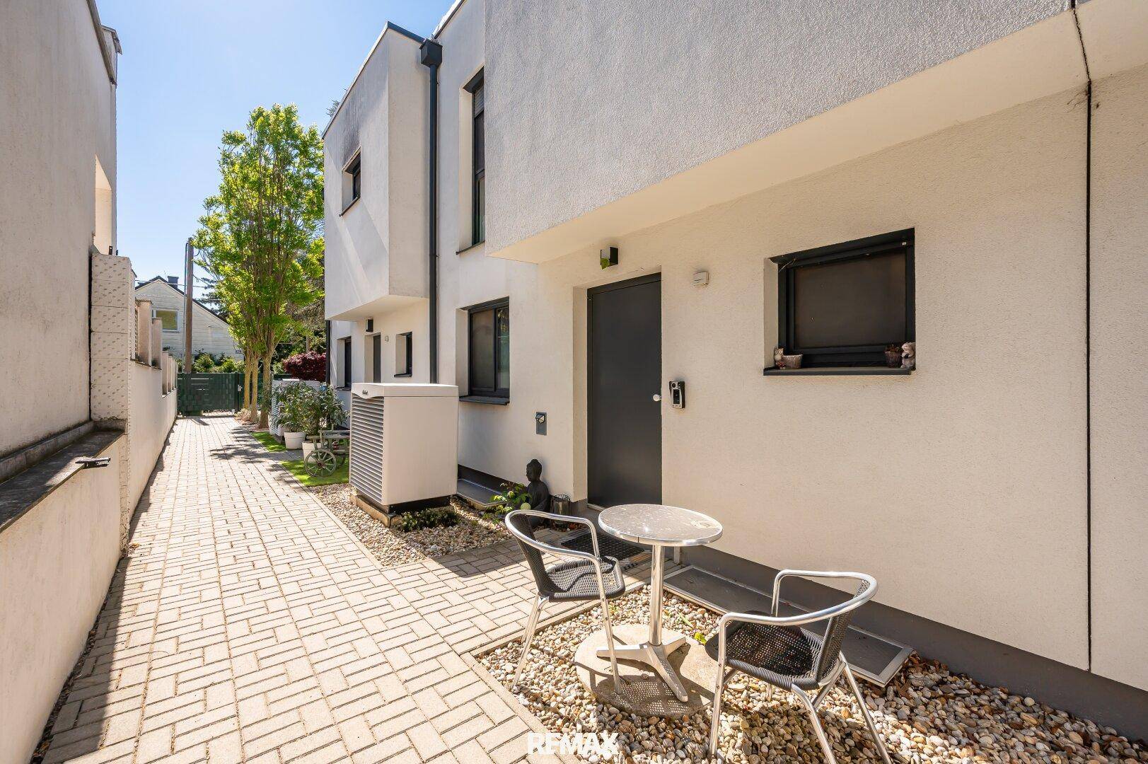 Außenbereich eines modernen Gebäudes mit kleiner Terrasse und Kiesbeet.