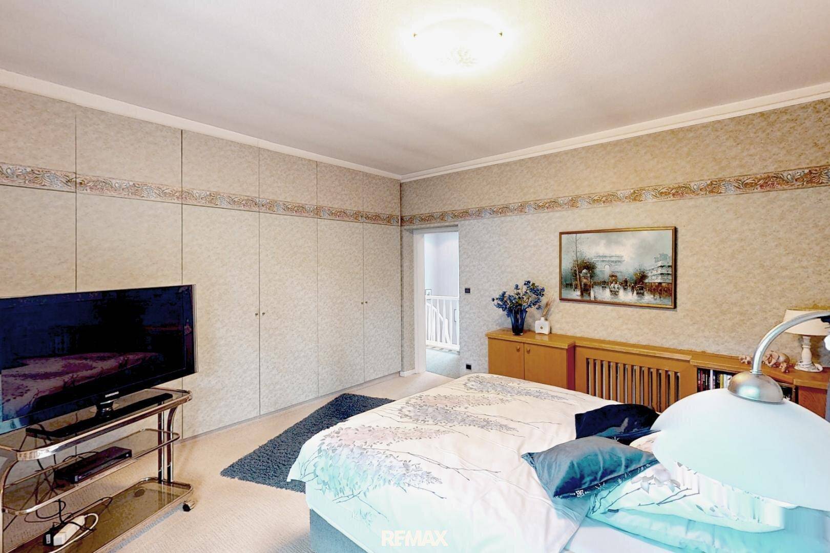 Gemütliches Schlafzimmer mit großem Bett, Einbauschränken und Teppichboden für Komfort.