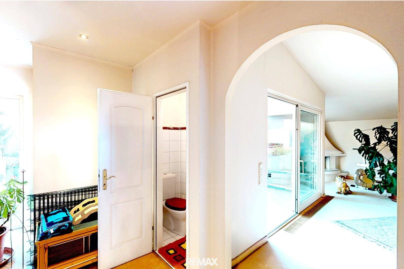 Heller Flur mit elegantem Bogen, Zugang zu einer Gästetoilette und Blick in den Wohnbereich.
