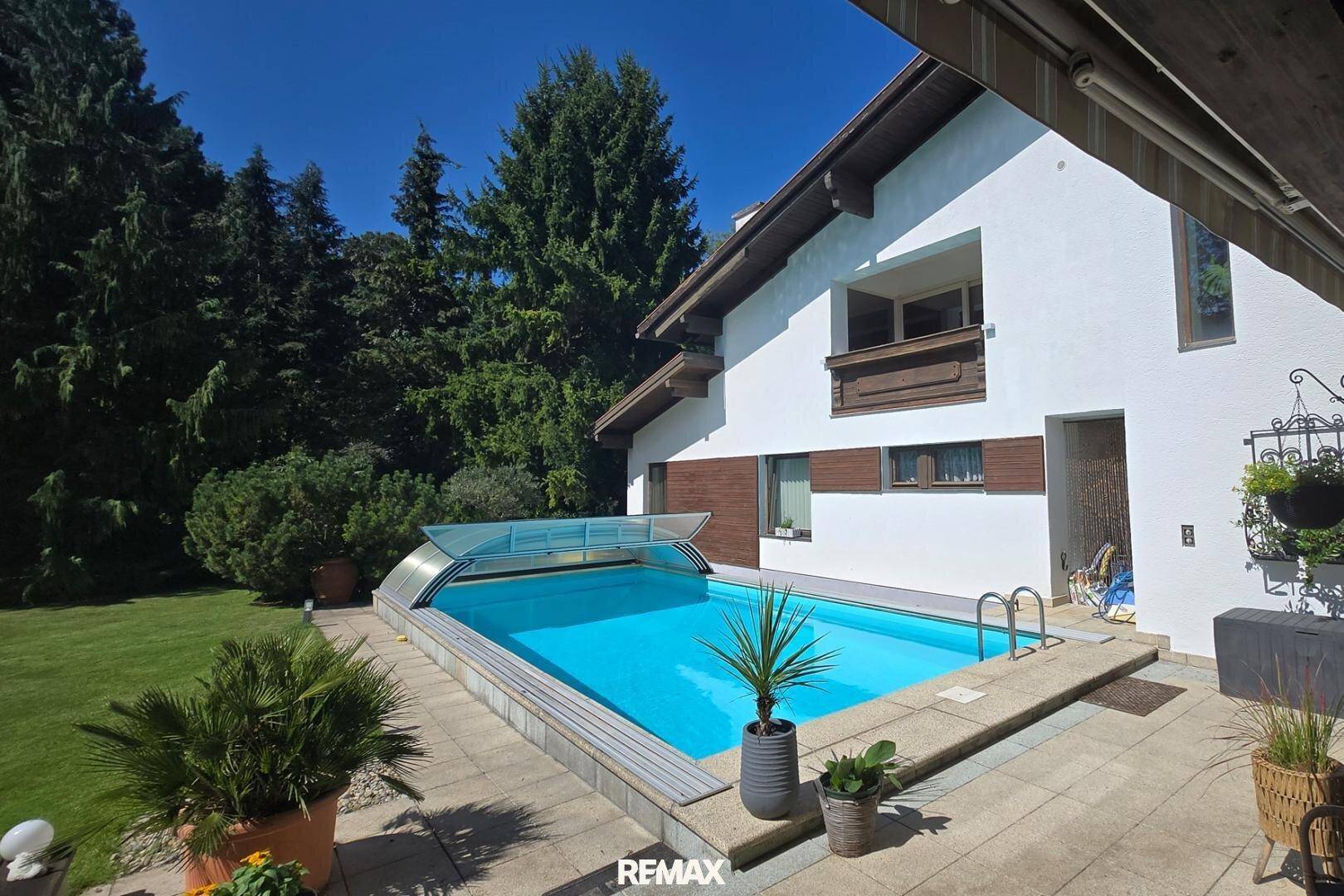 Großer Außenbereich mit privatem Pool, umgeben von einem gepflegten Garten und hohen Bäumen.