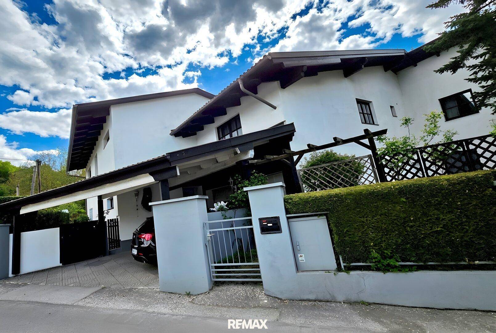 Die moderne Fassade des Hauses mit Carport und gepflegter Hecke am Eingangsbereich.