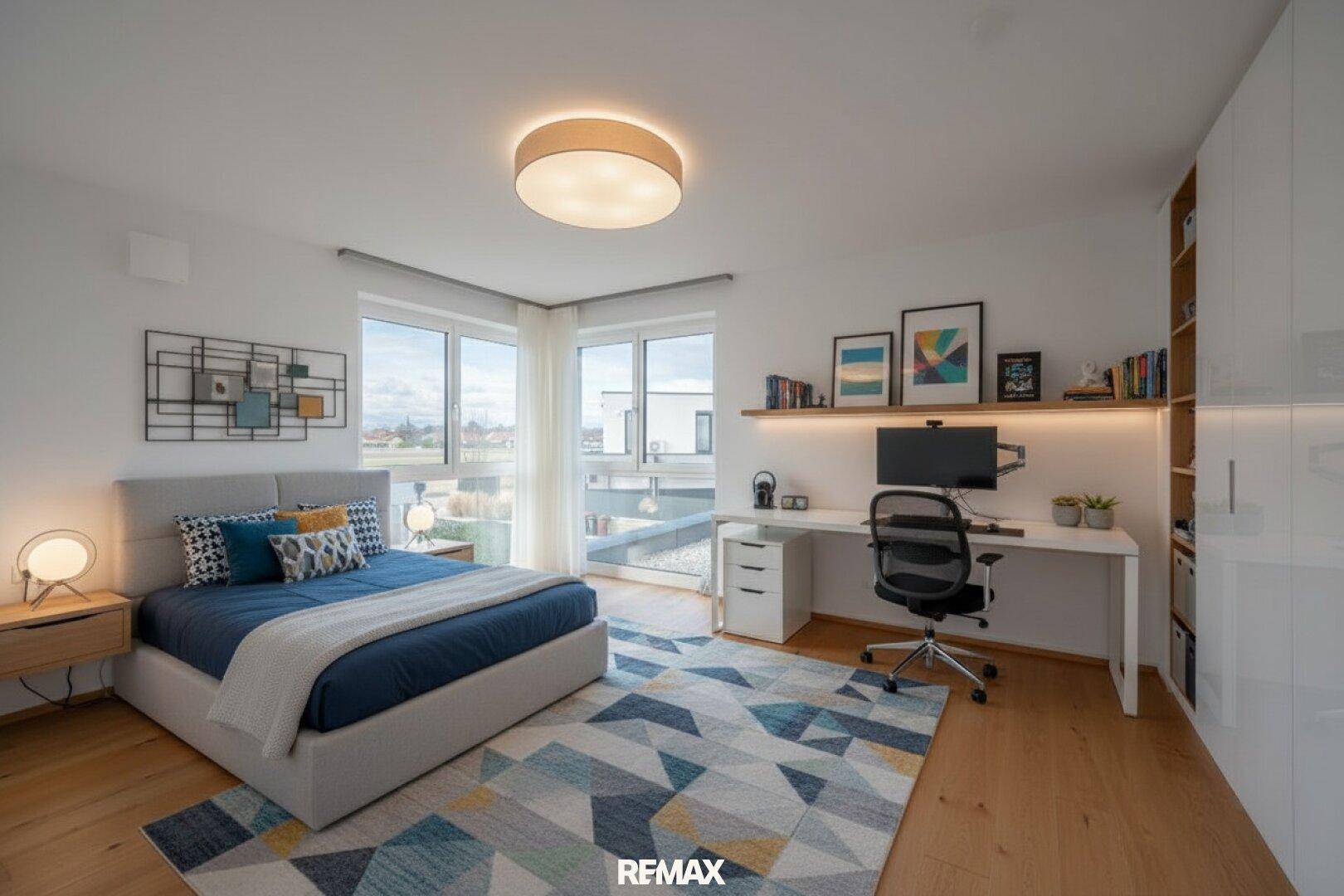 Helles Schlafzimmer mit Bett, Schreibtisch, Bücherregal und großen Fenstern mit Ausblick.