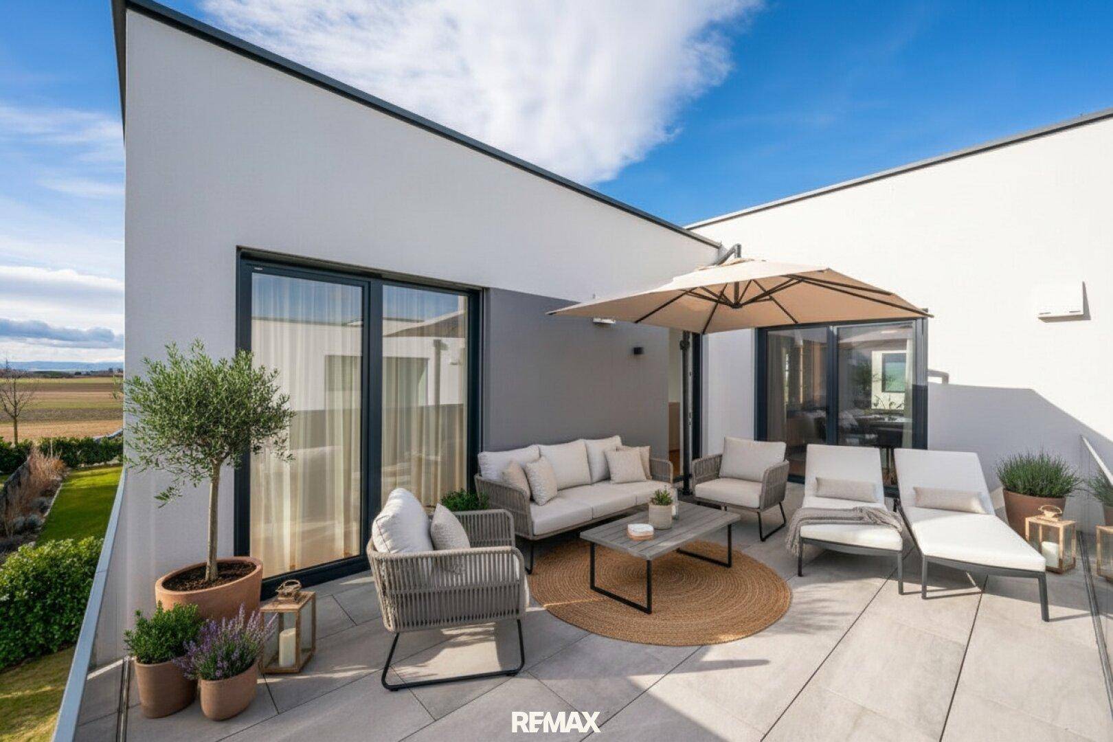 Geräumige Terrasse mit stilvollen Loungemöbeln, Sonnenschirm und weitem Blick ins Grüne.