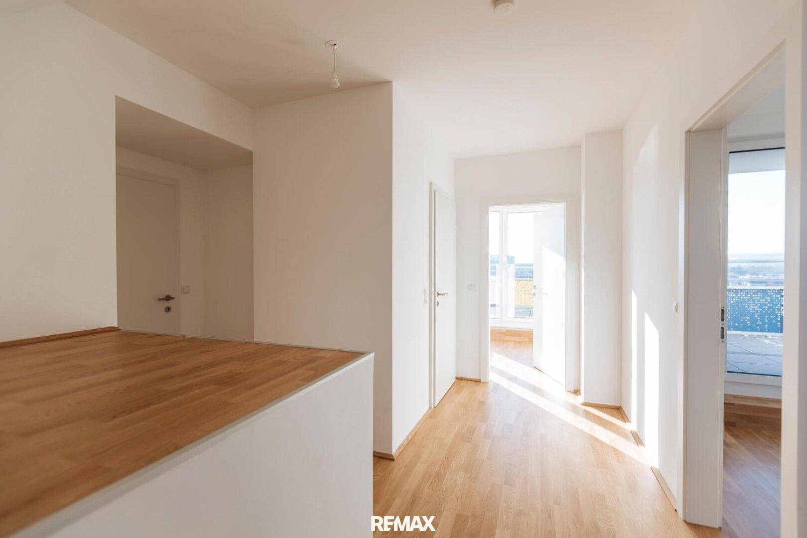 Lichtdurchfluteter Flur mit Holzboden und mehreren Türen, der zu weiteren Räumen führt.