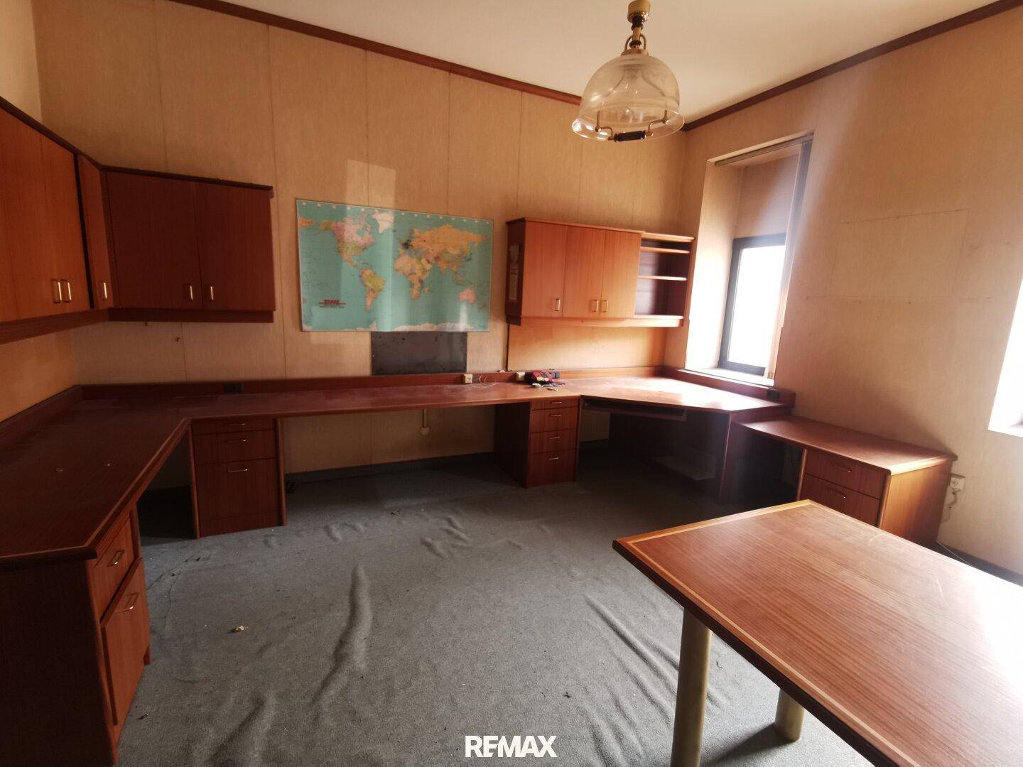 Geräumiges Büro mit eingebauten Holzschreibtischen, Schränken und einer Weltkarte.