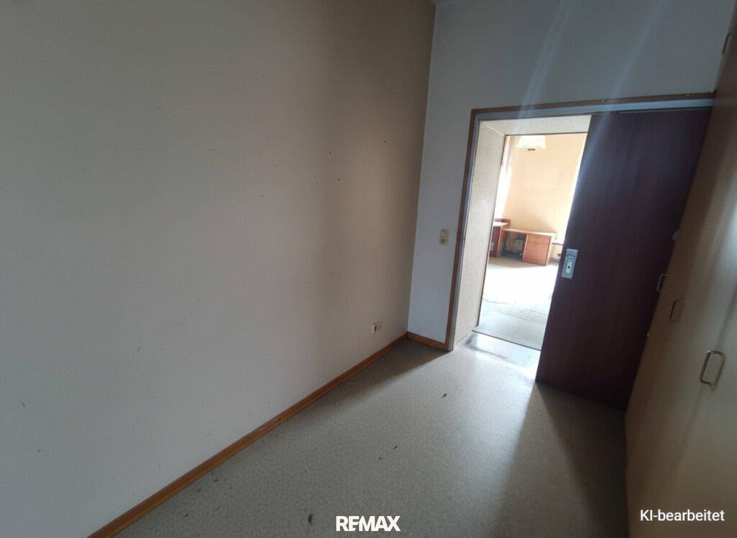 Schmaler Flur mit hellem Vinylboden und Zugang zu einem weiteren Zimmer.