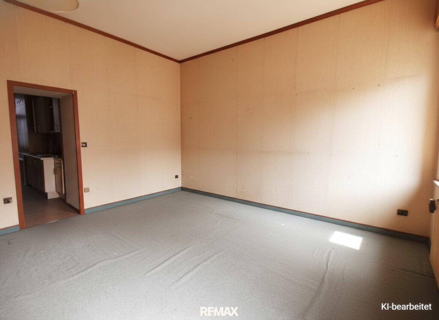 Geräumiger Raum mit Teppichboden und Holzvertäfelung, mit Zugang zu einem Nebenraum.