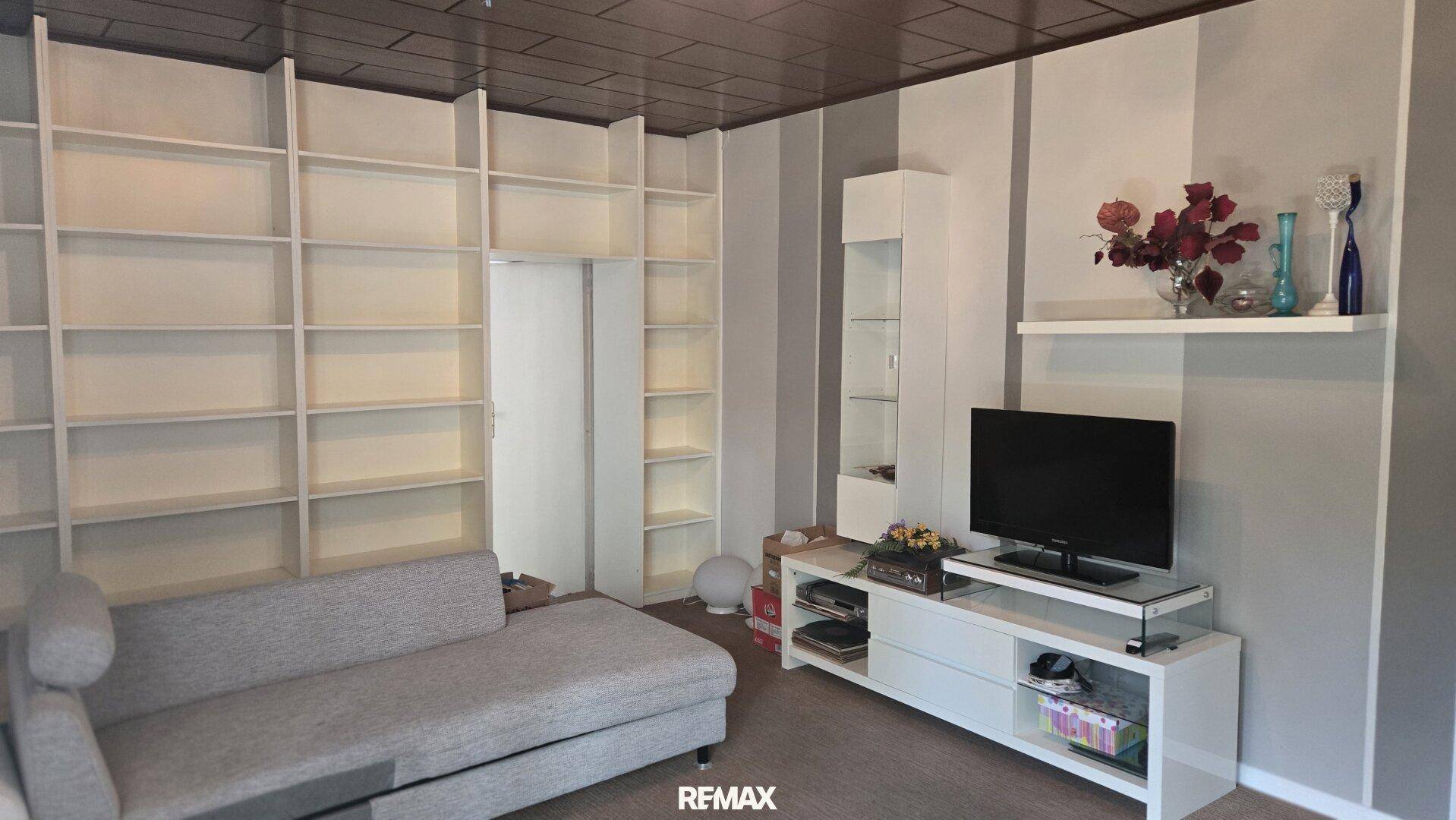 Wohnraum mit großen Einbauregalen, gemütlichem Sofa und Fernseher, ideal als Medienzimmer.