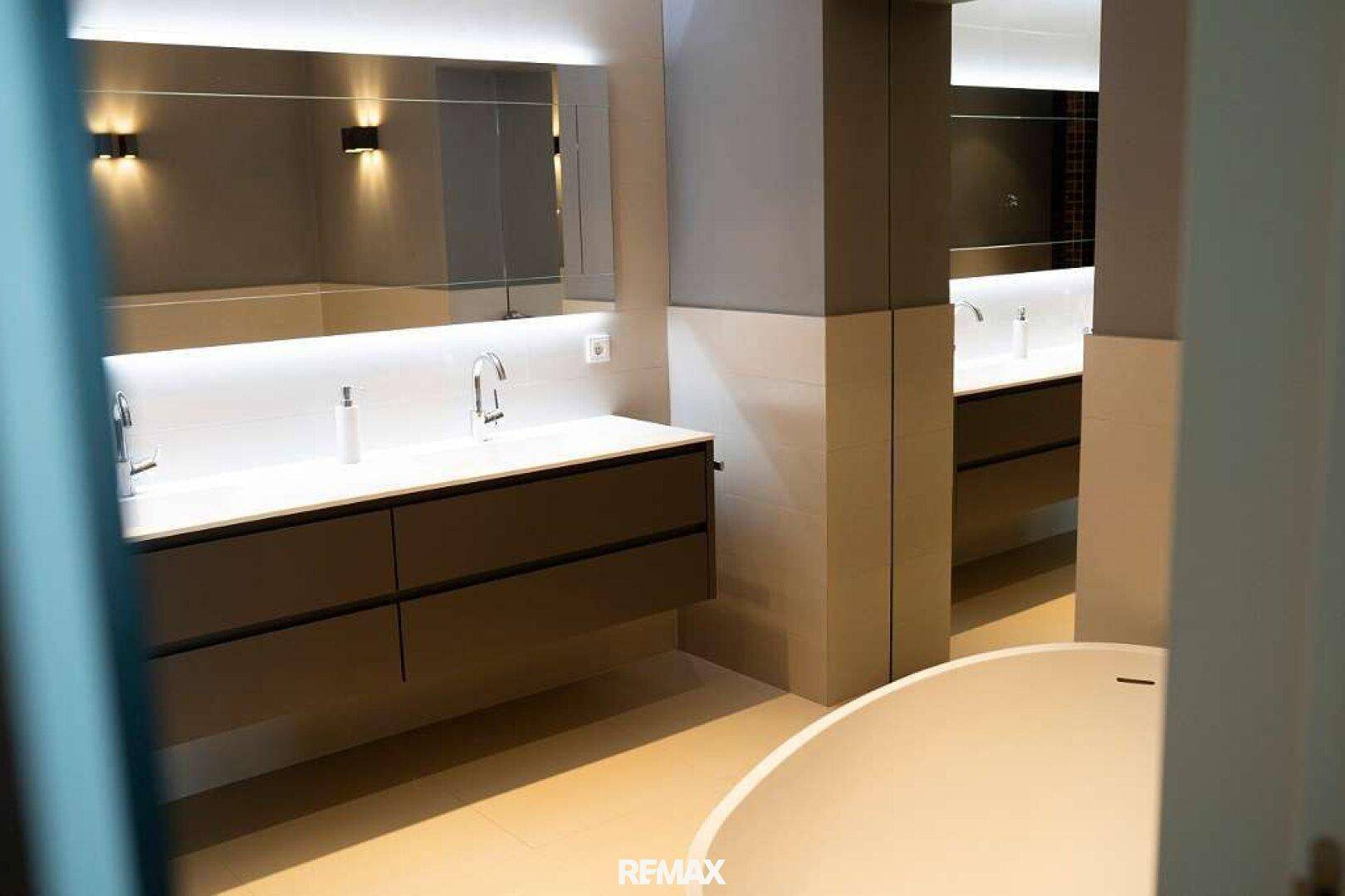 Elegantes Badezimmer mit Doppelwaschbecken, großem Spiegel und einer freistehenden Badewanne.