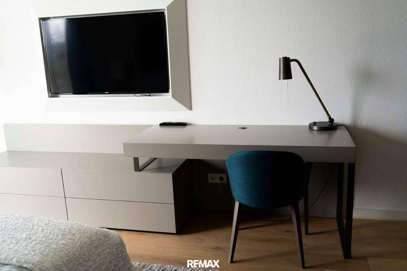 Modernes Schlafzimmer mit Schreibtisch, Fernseher und integrierten Möbeln.