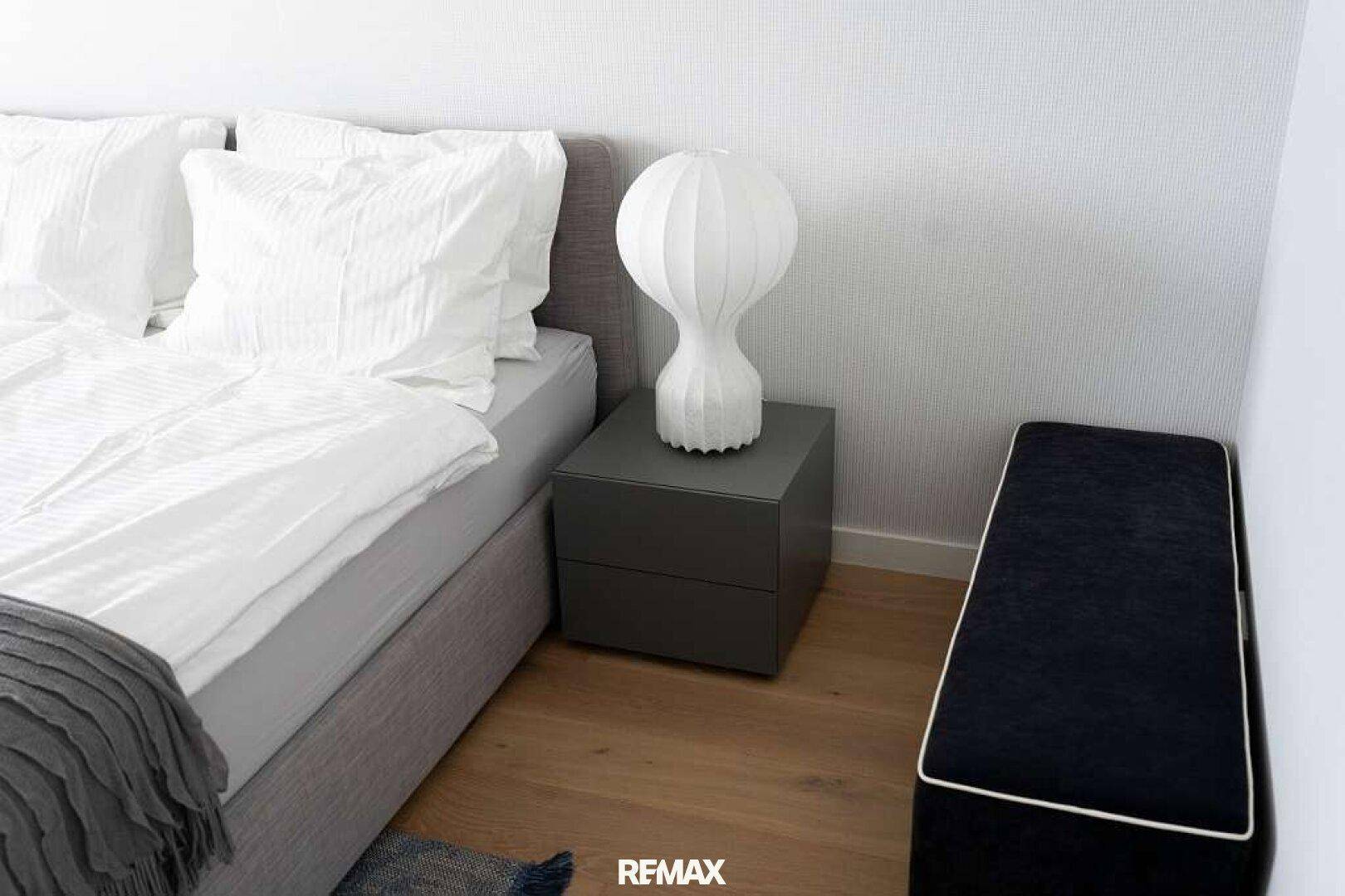 Gemütliches Schlafzimmer mit Doppelbett, Nachttisch und moderner Lampe.