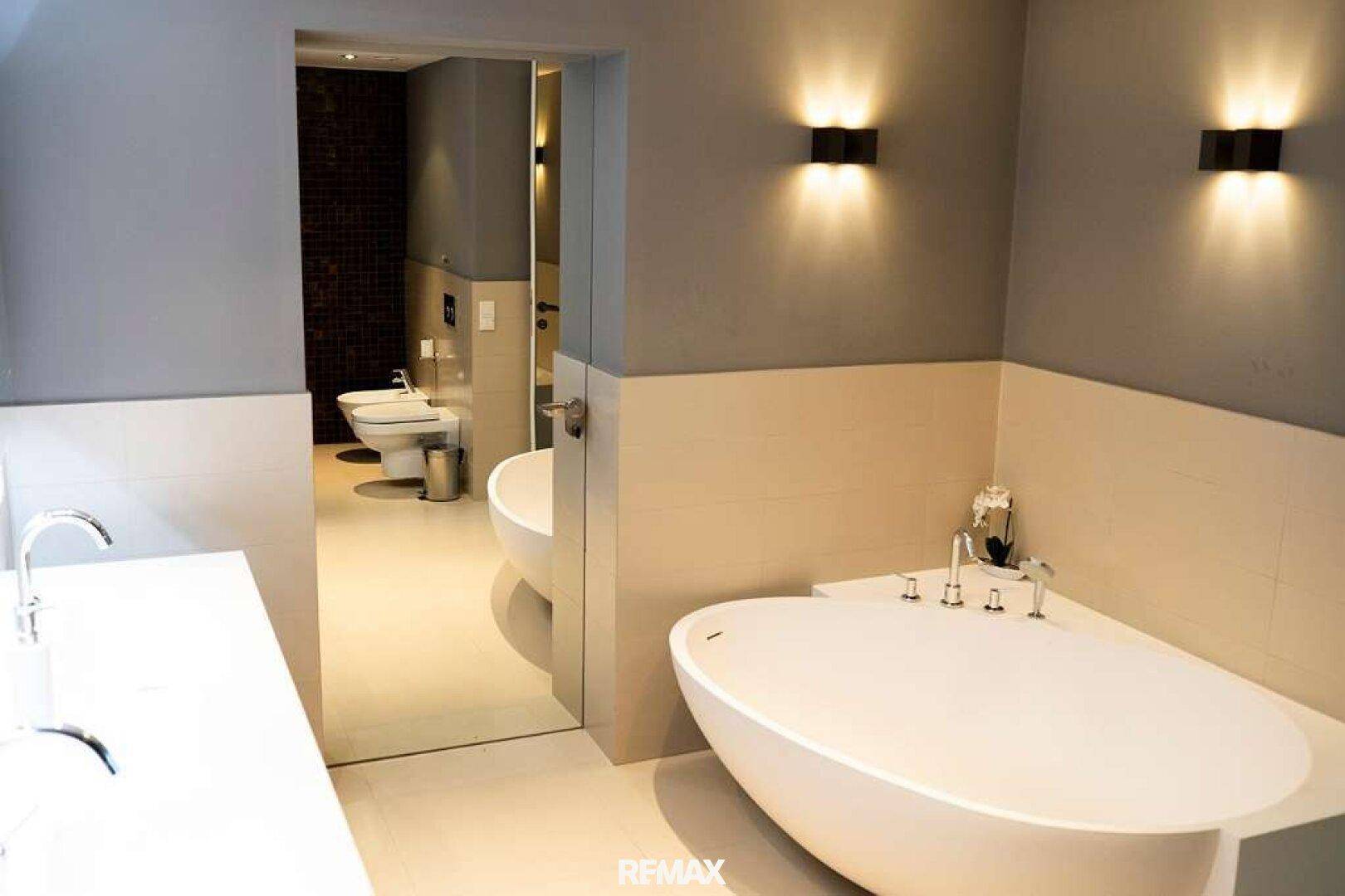 Modernes Badezimmer mit freistehender Badewanne und separatem WC-Bereich.
