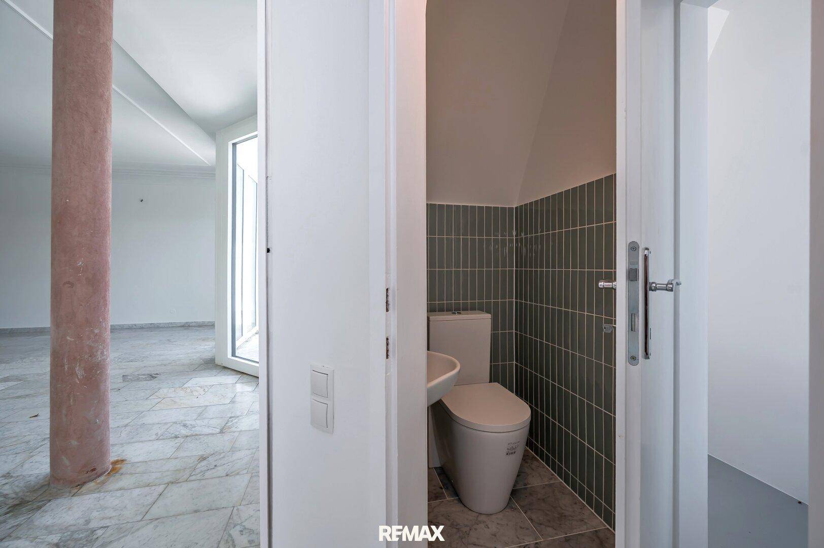 Kleines Gäste-WC mit modernen grünen Fliesen und wandmontierter Toilette.