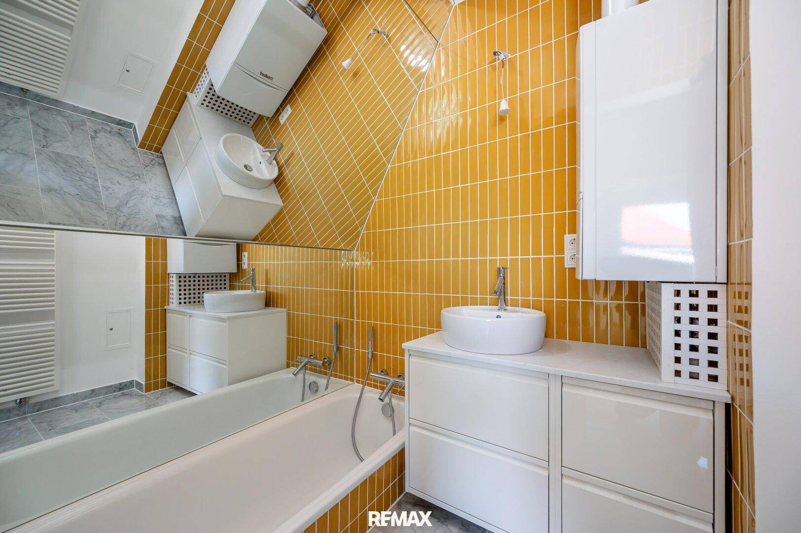 Modernes Badezimmer mit gelben Fliesen, Badewanne und Waschbecken, unter Dachschräge.