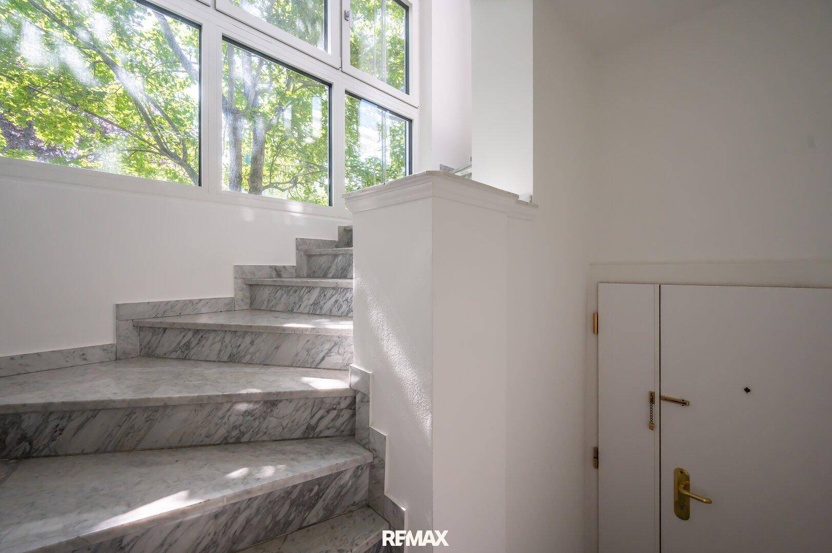 Elegante Marmortreppe mit großen Fenstern, die viel natürliches Licht hereinlassen.