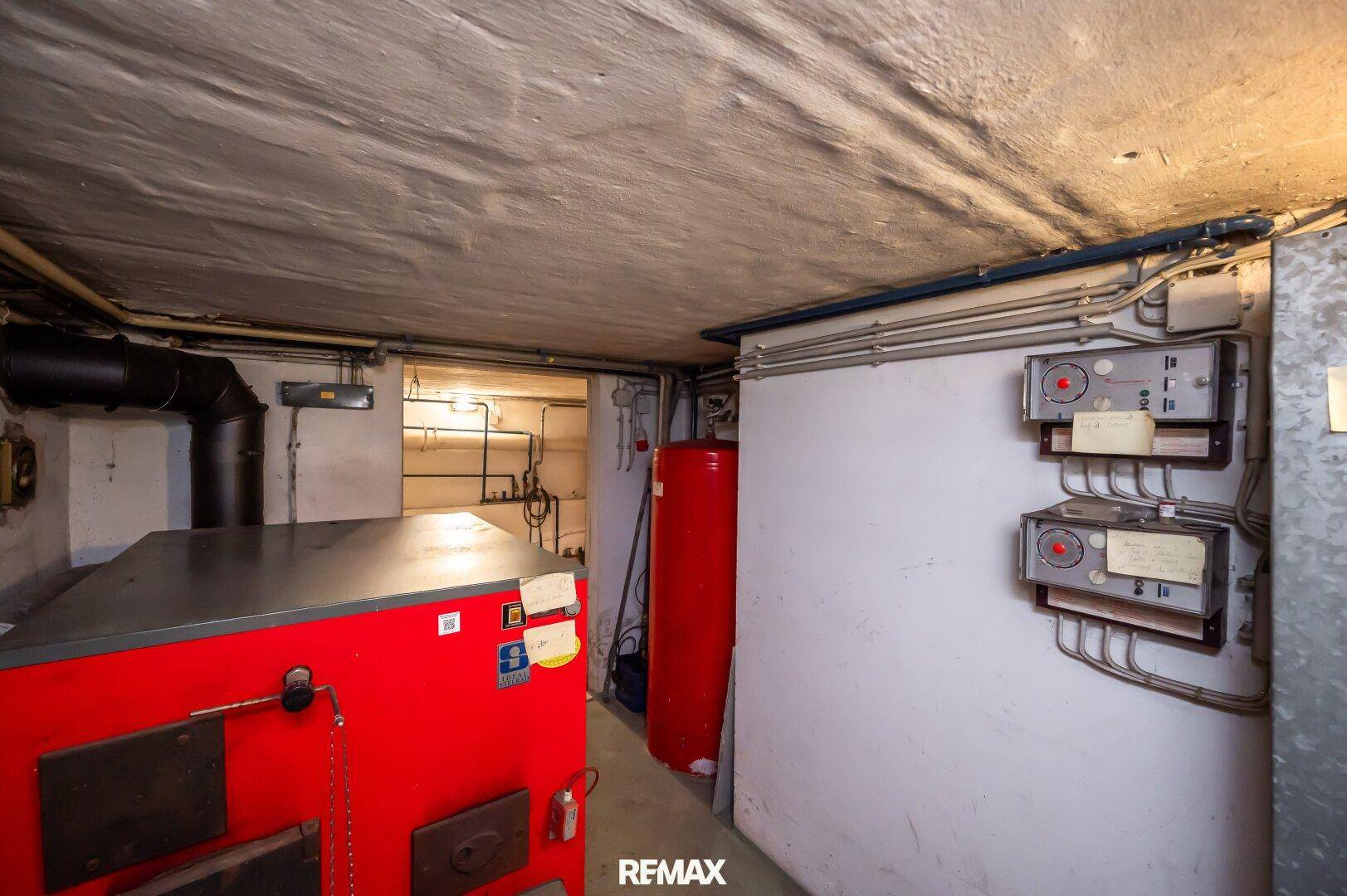 Heizungsraum im Keller mit großem Heizkessel und sichtbaren Installationen für die Gebäudetechnik.