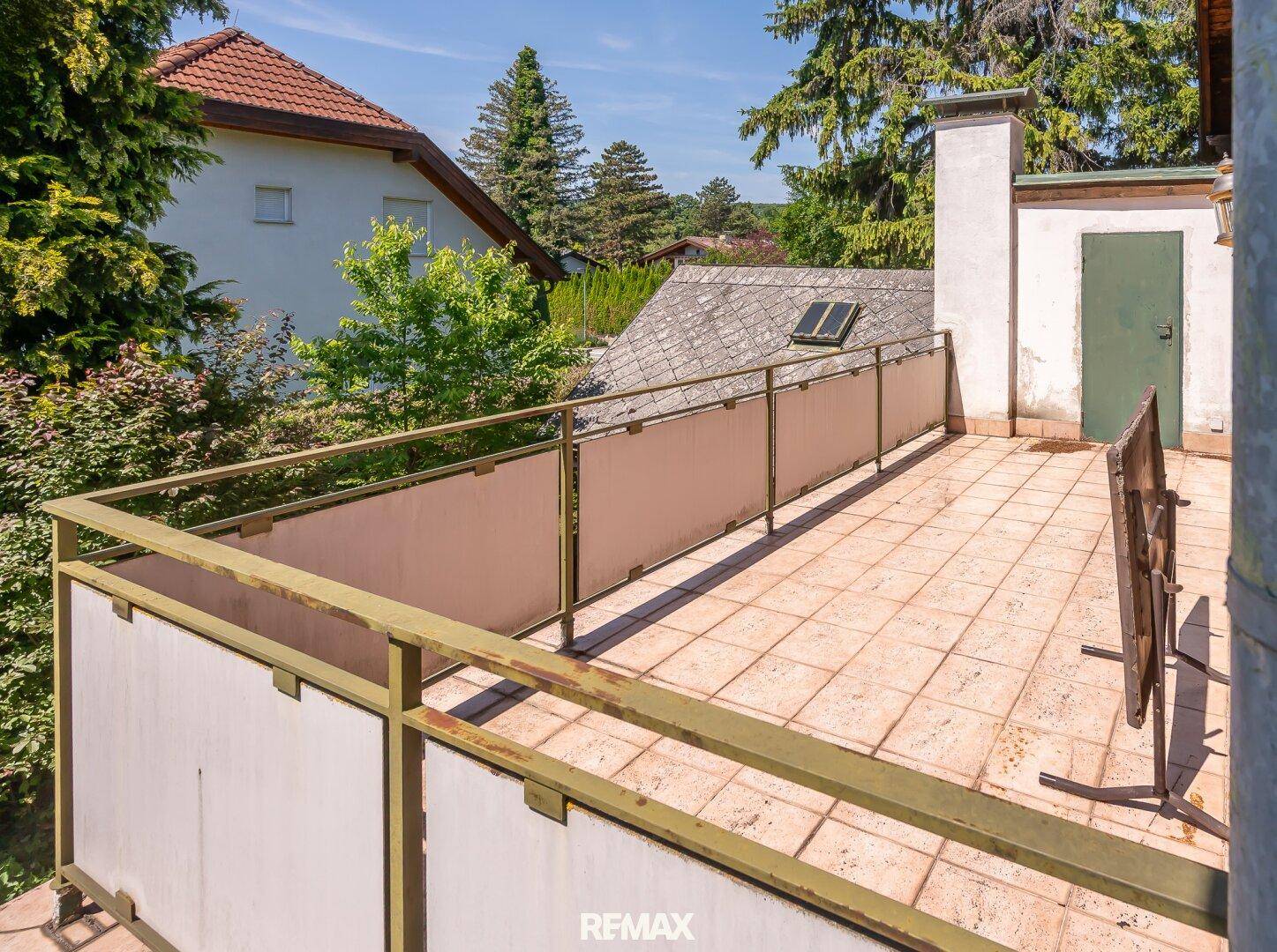 Große geflieste Terrasse mit Geländer und weitem Blick über die Dächer und die Umgebung.