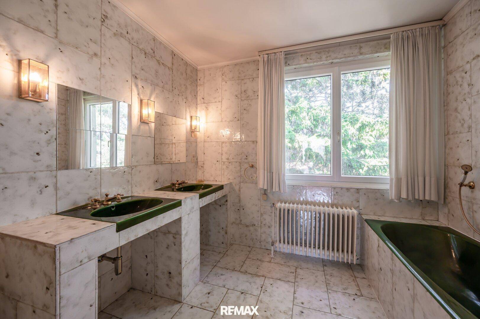 Geräumiges Badezimmer mit Marmorfliesen, Doppelwaschbecken und grüner Badewanne.