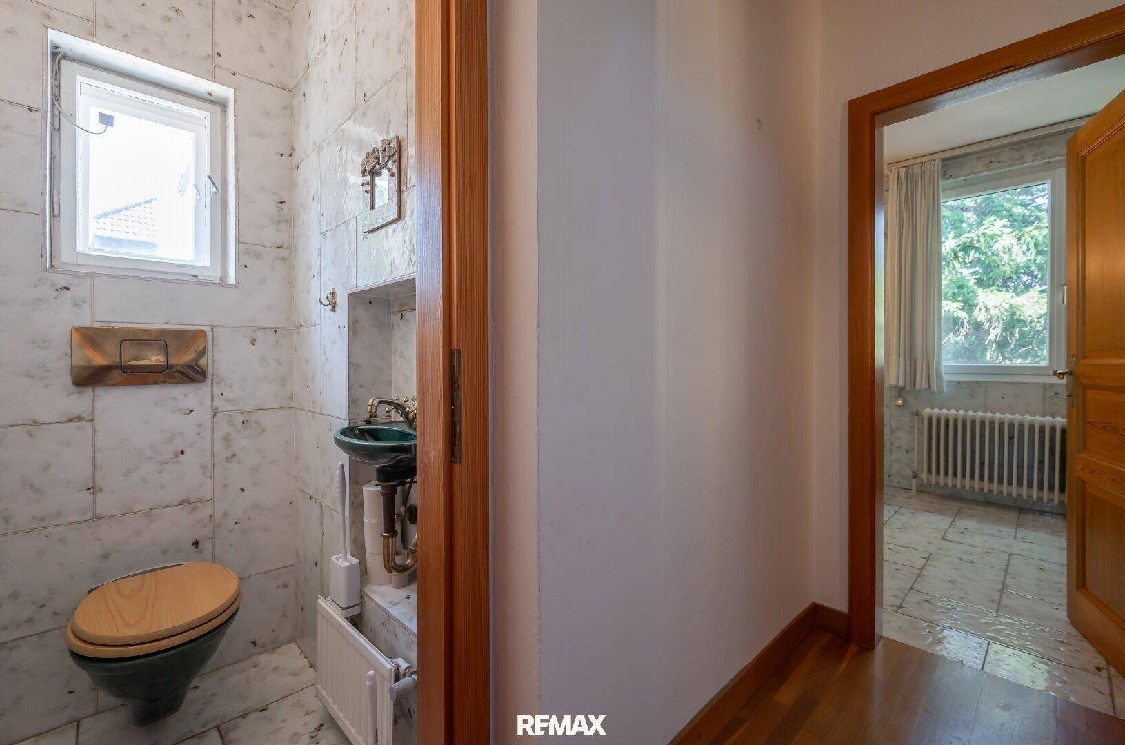 Kleines Gäste-WC mit Marmorfliesen, Fenster und traditionellem Waschbecken.