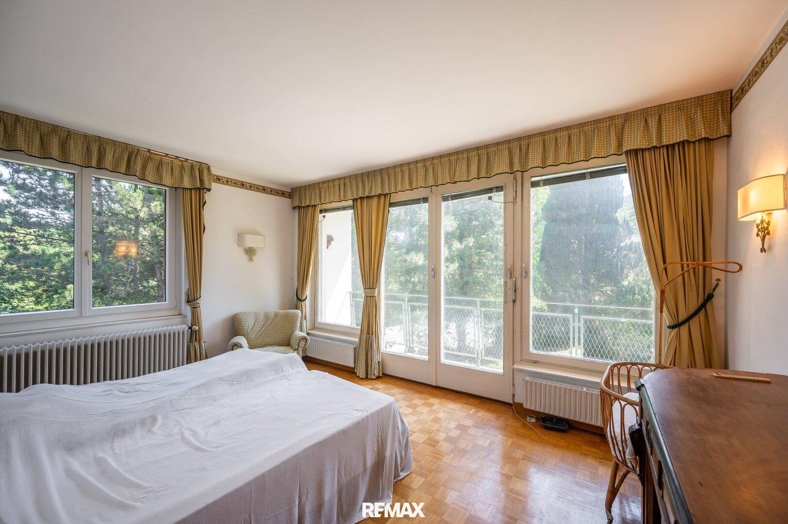 Geräumiges Schlafzimmer mit Parkettboden, großen Fenstern und Zugang zum Balkon.