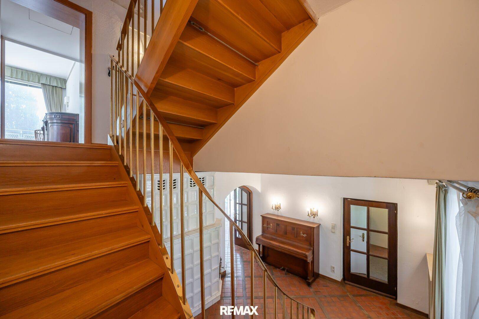 Elegante Holztreppe mit Metallgeländer, die die oberen Etagen des Hauses verbindet.