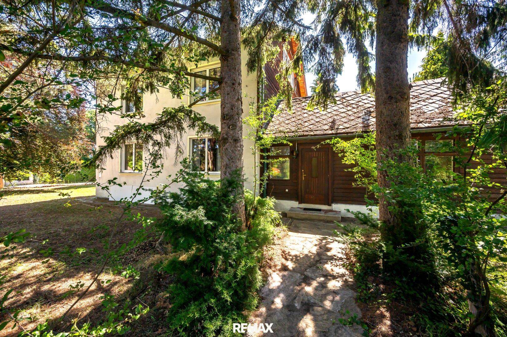 Eingangsbereich des Hauses, umgeben von dichtem Grün und hohen Bäumen, bietet Privatsphäre.