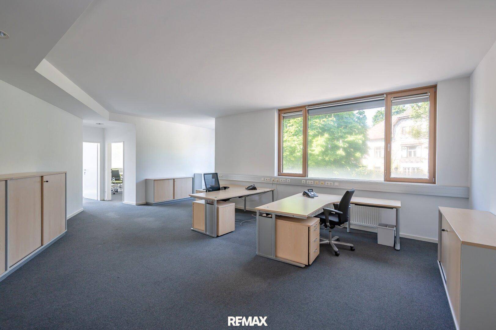 Funktional eingerichtetes Büro mit Schreibtischen, Schränken und Teppichboden.