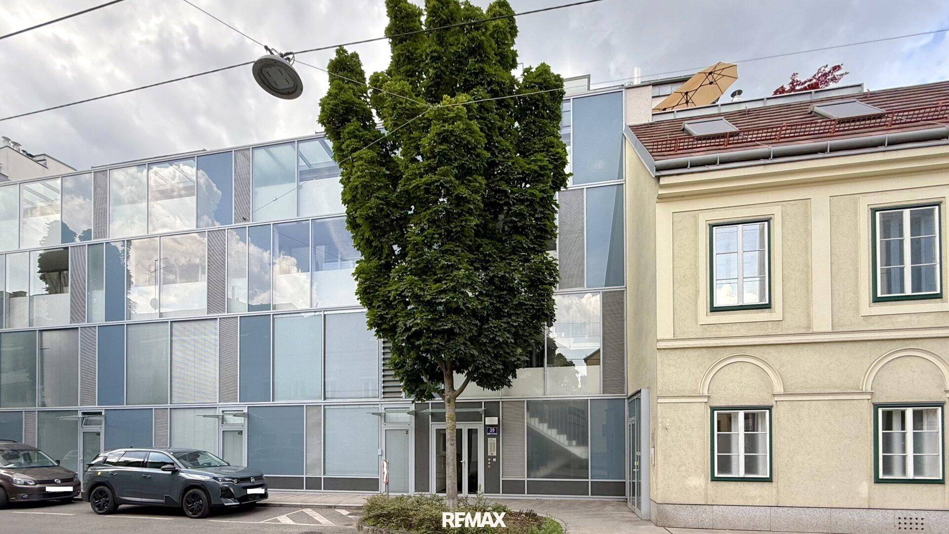 Moderne Glasfassade neben einem traditionellen Gebäude in der Stadt, die einen interessanten Kontrast bildet.