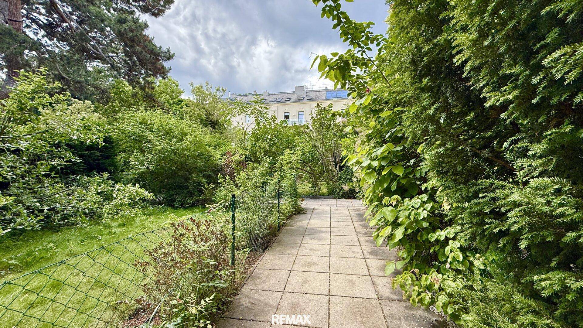 Gepflegter Gartenweg umgeben von üppigem Grün und Sträuchern, der zum Spazierengehen einlädt.