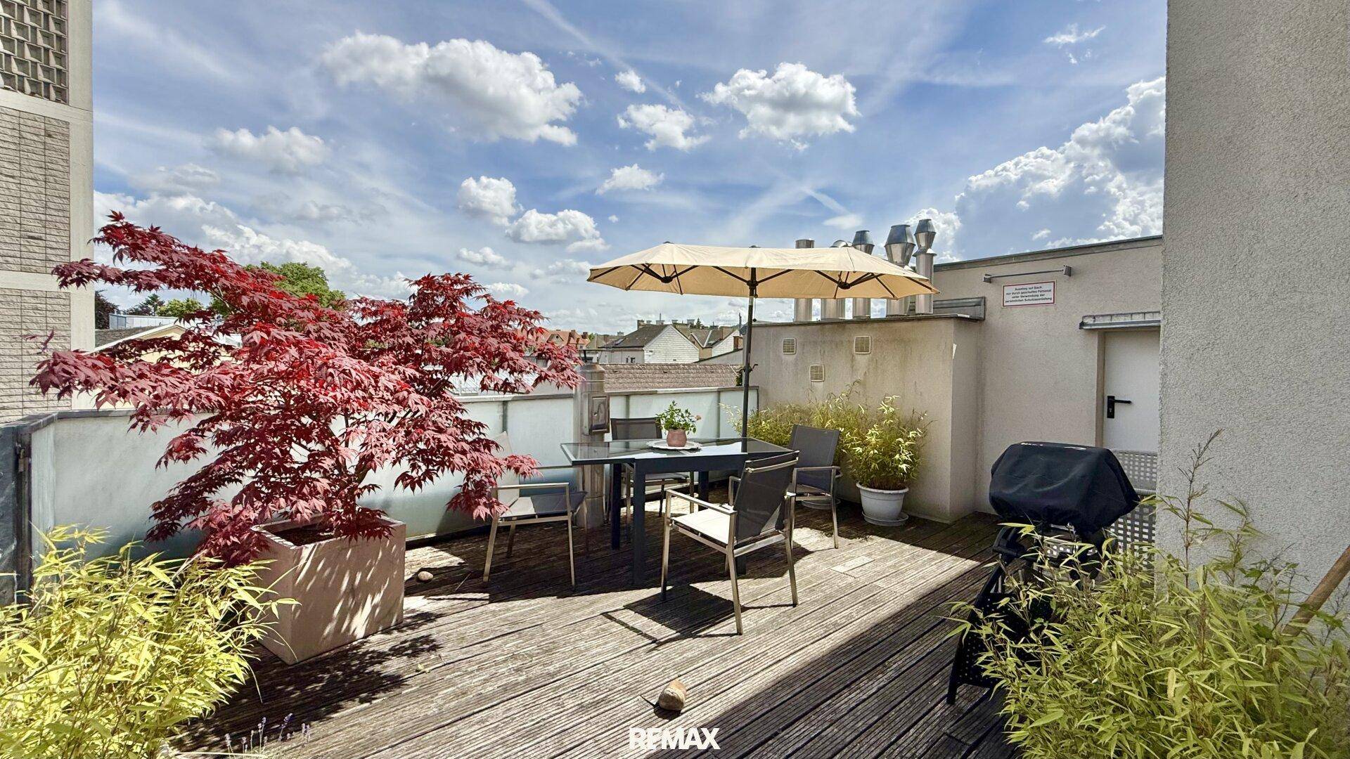 Weitläufige Dachterrasse mit Holzboden, Grill und Sitzbereich, ideal für entspannte Stunden im Freien.