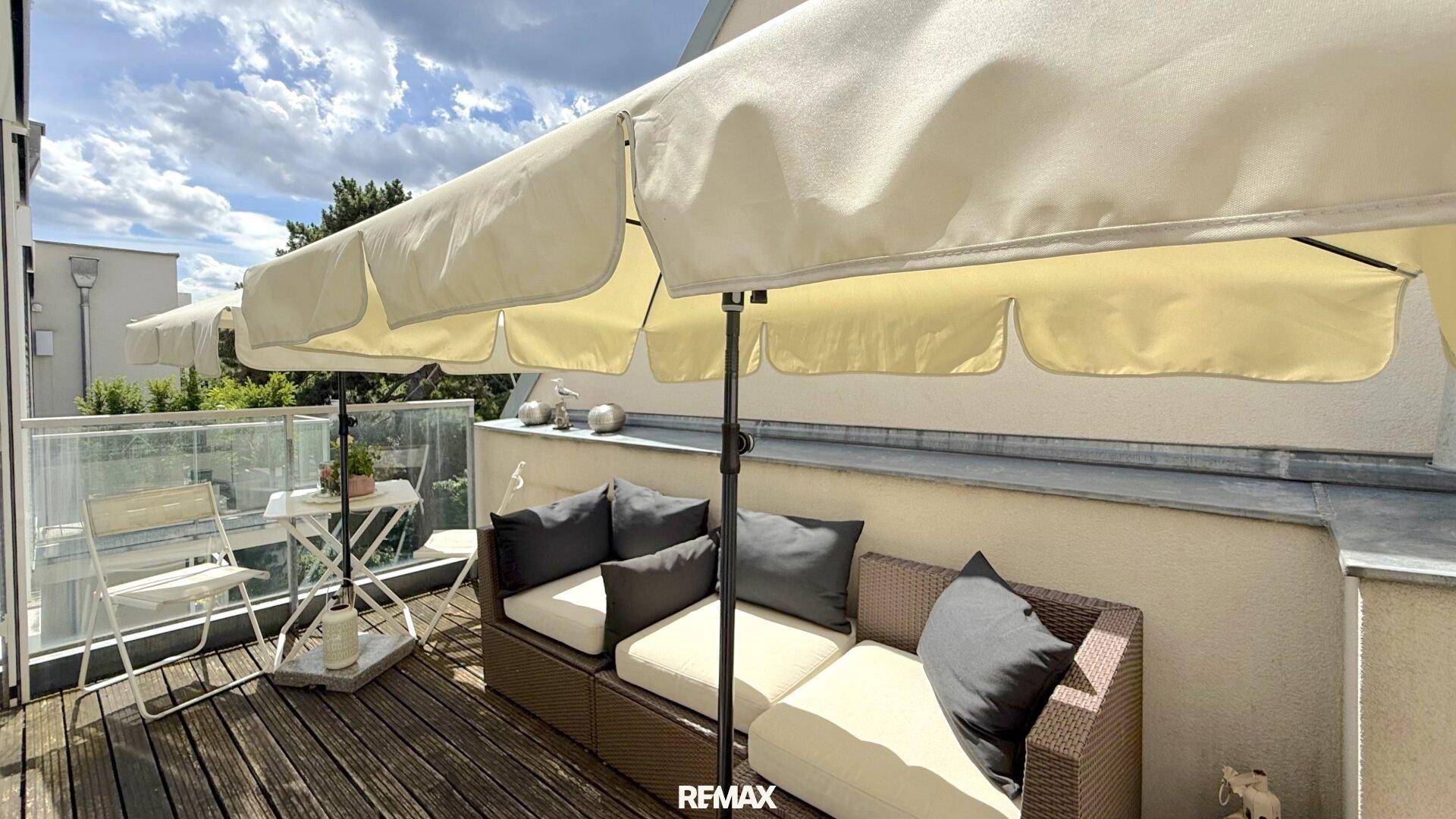 Gemütlicher Balkon mit bequemen Sitzmöbeln und großem Sonnenschirm, ideal zum Entspannen.