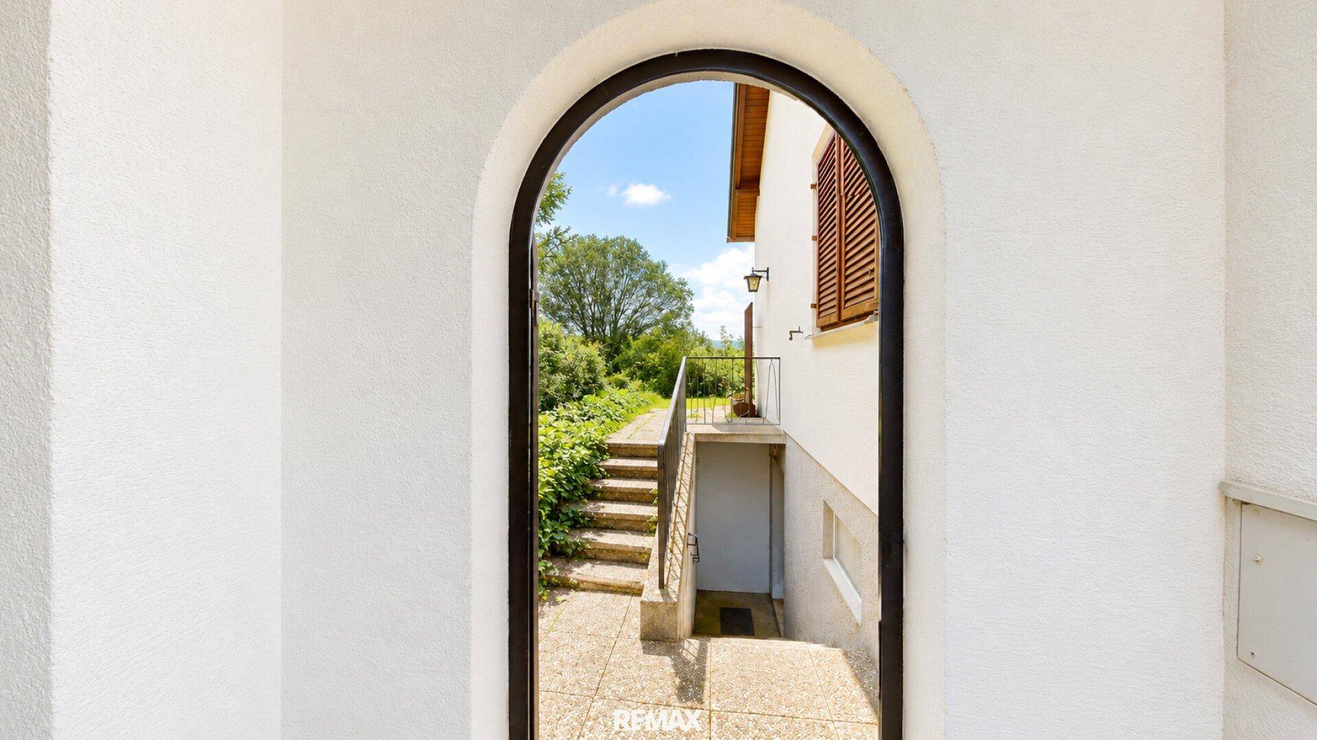 Gewölbter Eingangsbereich mit Treppe, die zum Keller und einem Gartenweg führt.