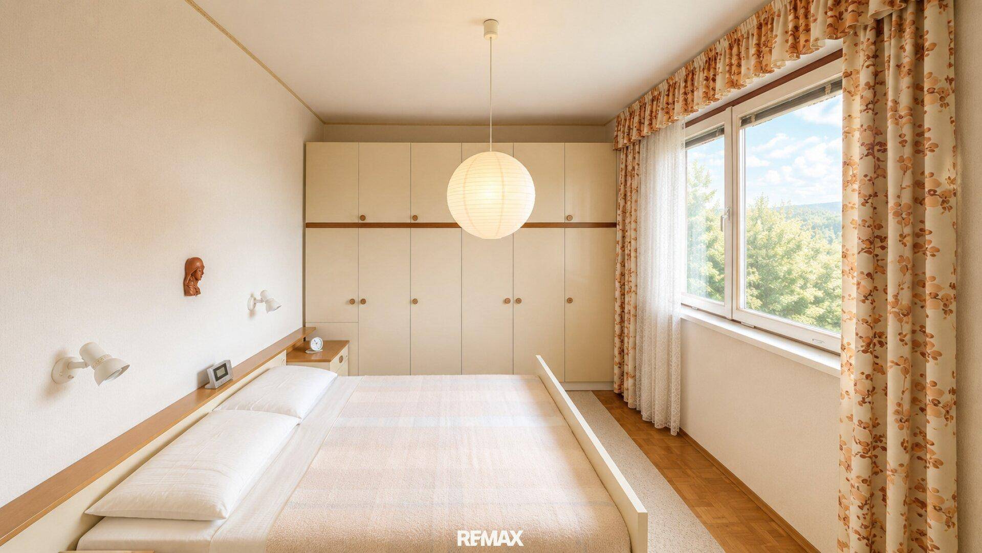 Helles Schlafzimmer mit Einbauschränken, Doppelbett und Fenster mit Blick ins Grüne.