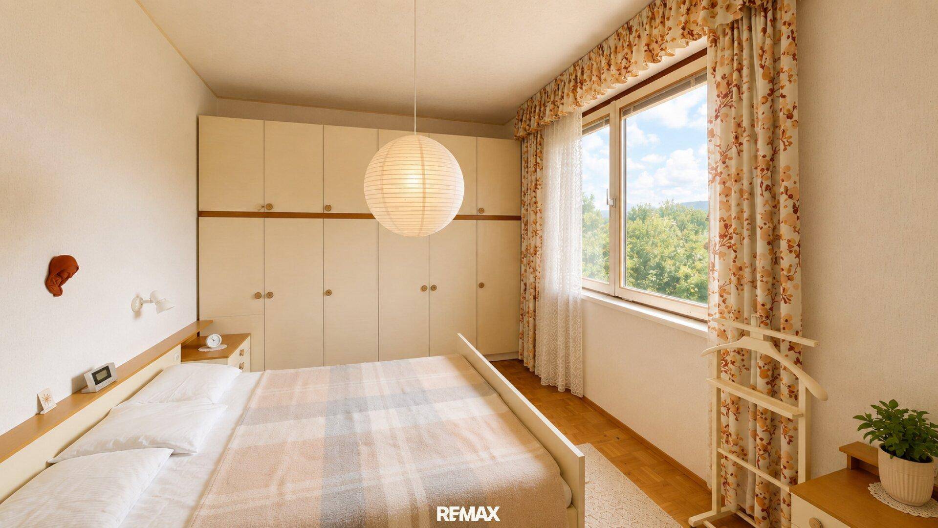 Geräumiges Schlafzimmer mit Einbauschränken, Doppelbett und großem Fenster mit Weitblick.