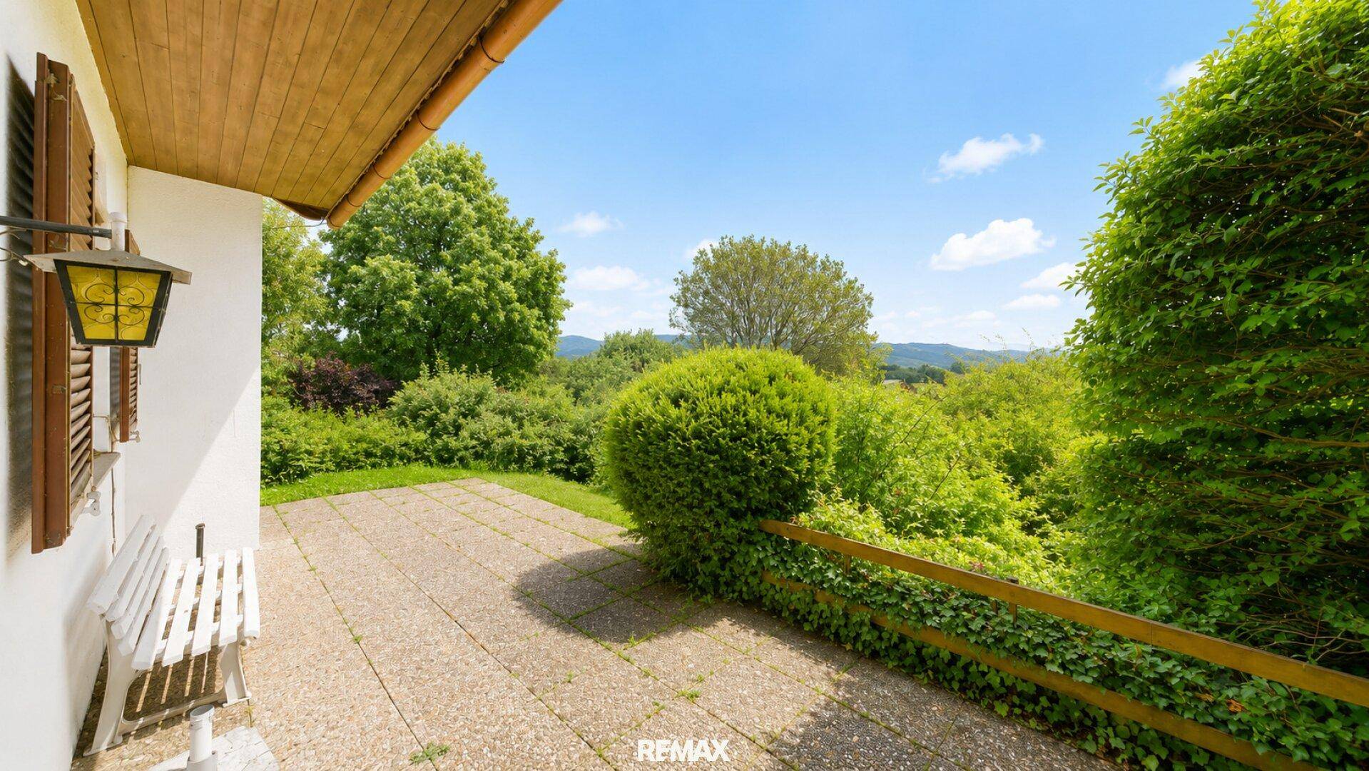 Geräumige Steinterrasse mit Sitzbank und Blick auf die grüne, hügelige Landschaft.