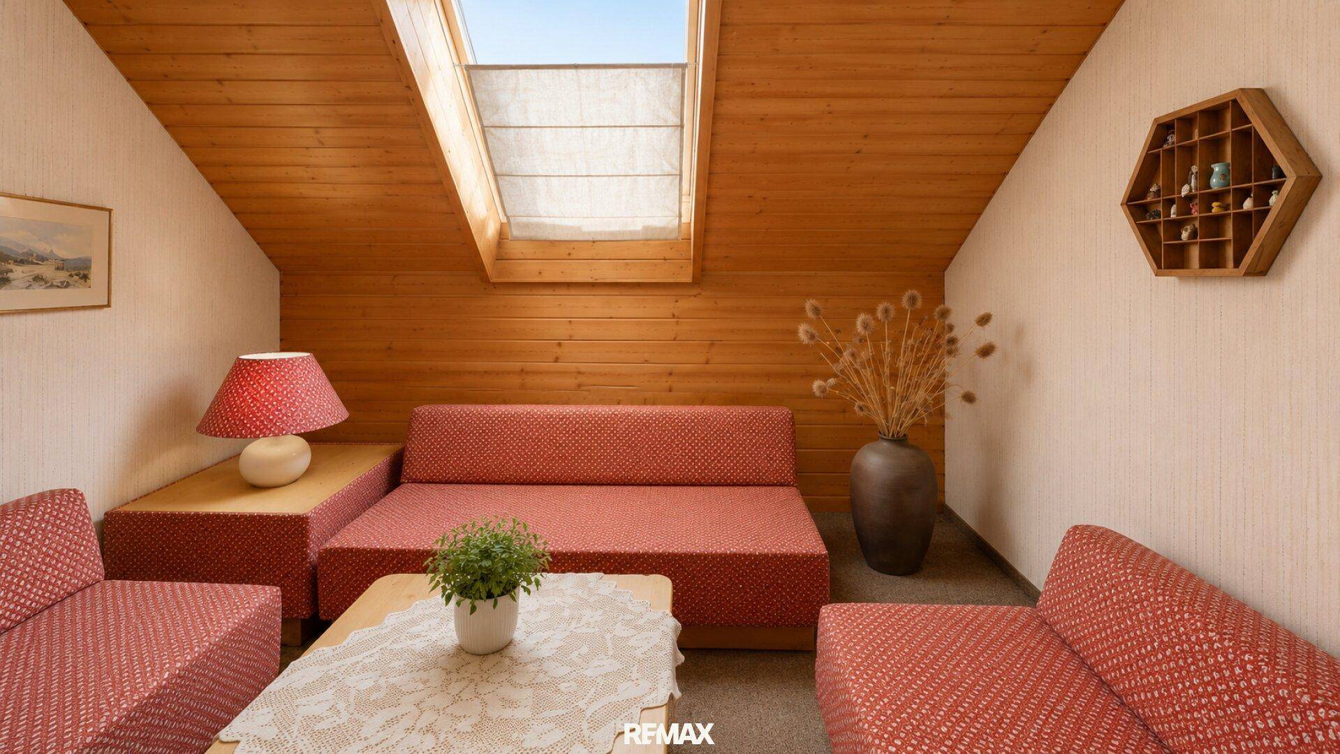 Gemütliches Wohnzimmer im Dachgeschoss mit Holzverkleidung, Dachfenster und traditionellen Möbeln.