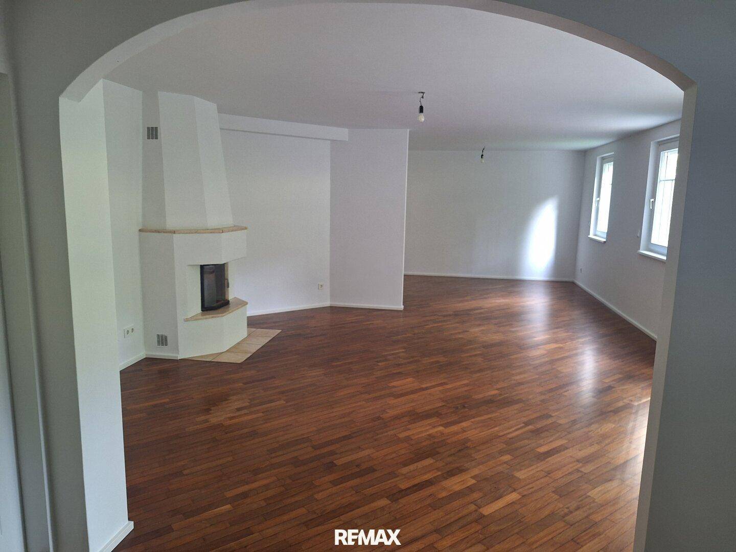 Geräumiges Wohnzimmer mit elegantem Parkettboden, einem gemütlichen Kamin und hellem Ambiente.