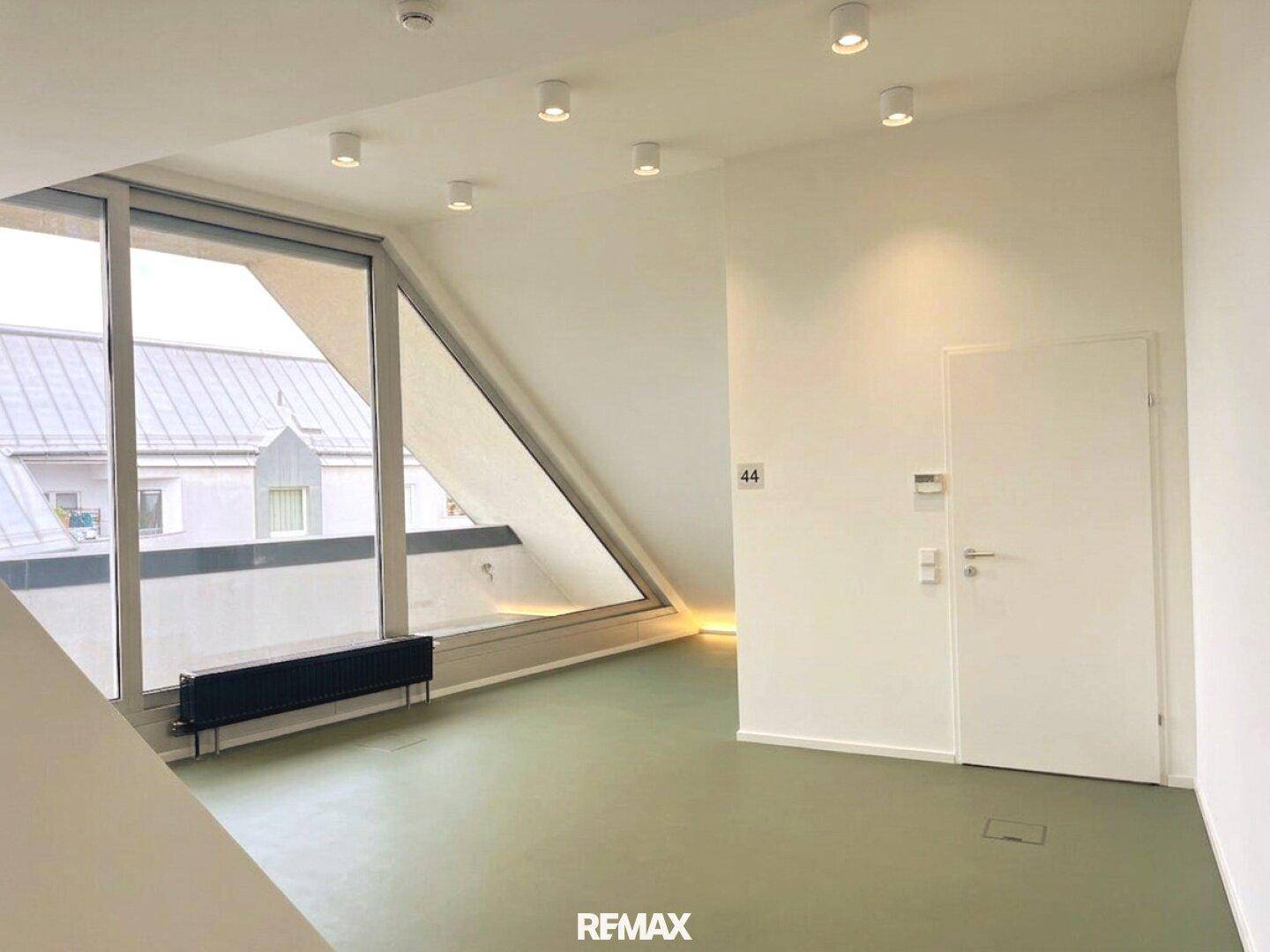 Heller Büroraum im Dachgeschoss mit schrägen Wänden, großen Fenstern und modernem Licht.