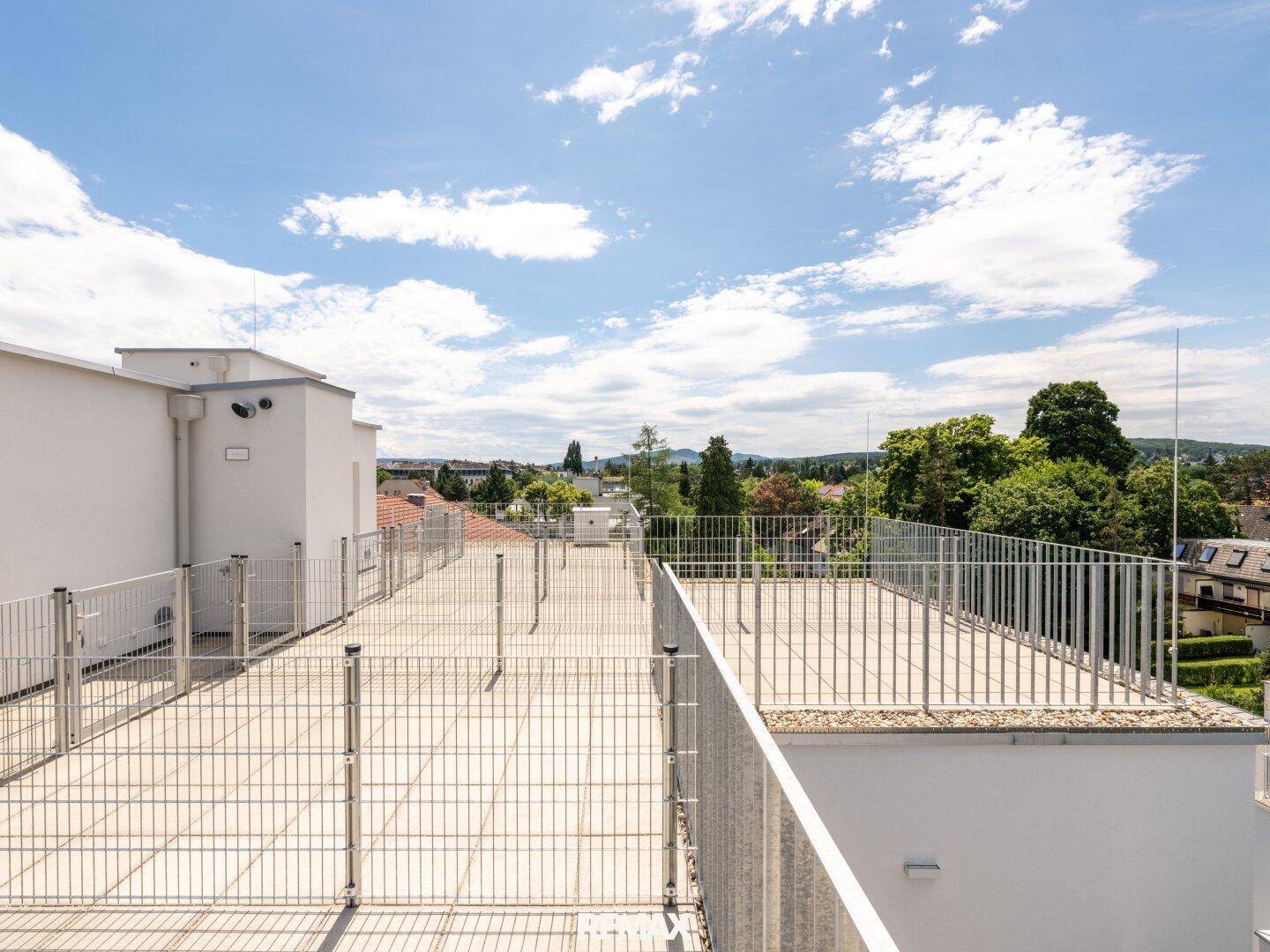 Weitläufige Dachterrasse mit Metallgeländer und Panoramablick auf die grüne Umgebung.