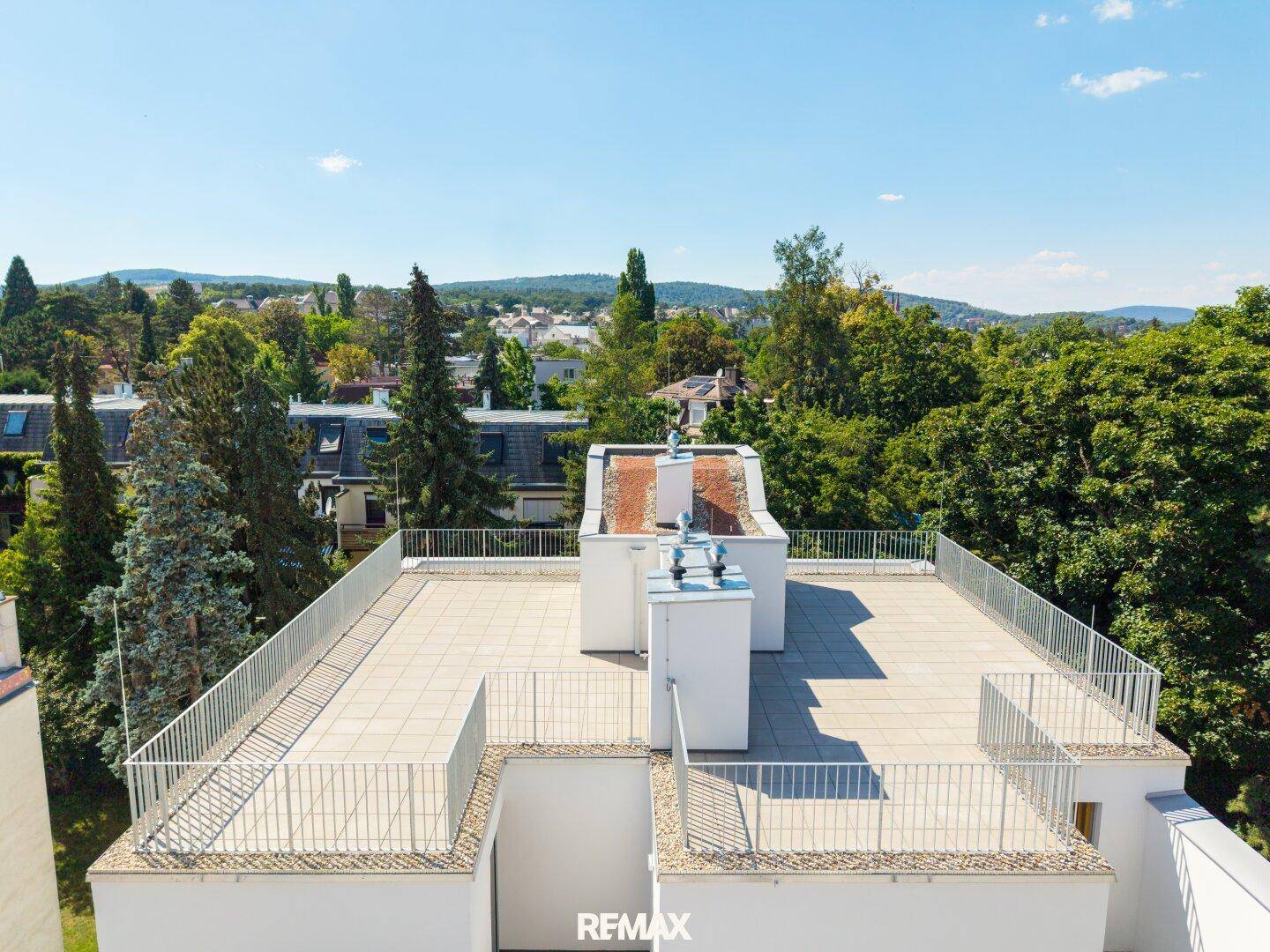 Weitläufige Dachterrasse mit Panoramablick über die grüne Umgebung und die umliegenden Gebäude.
