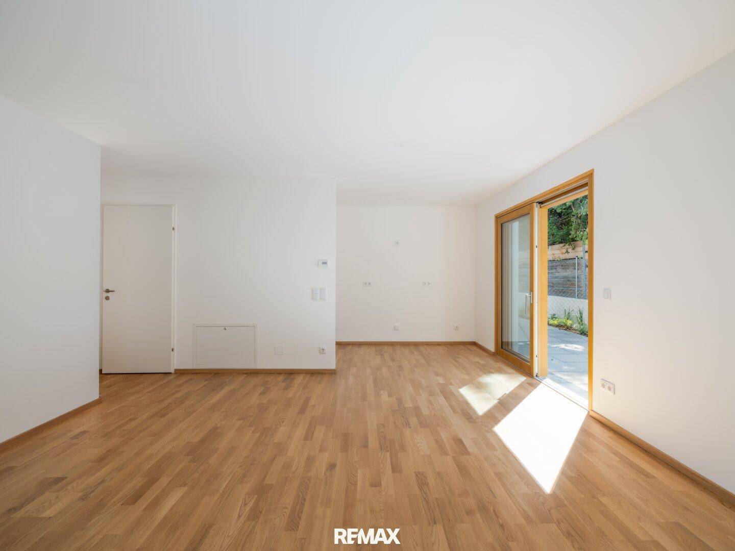 Geräumiges, helles Zimmer mit Holzboden und Zugang zu einem Außenbereich, ideal für flexible Gestaltung.