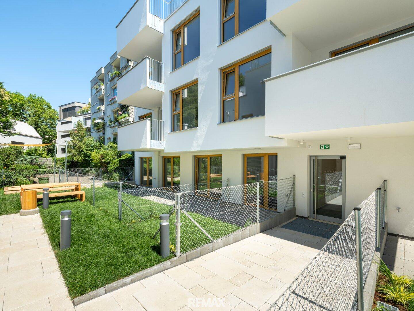 Kleiner Gartenbereich mit Rasenfläche, Sitzbank und Zugang zum Gebäude.